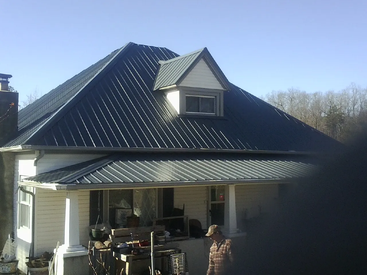 Dark blue standing seam metal roof with a dormer above a front porch in East Spencer