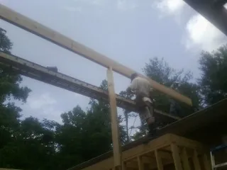 Carpenter setting a ridge beam over a new addition frame — Ice Dam Removal by Roofing Brothers in East Spencer