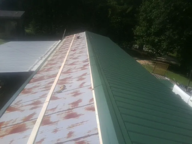 Old rusted panels beside newly installed green metal roofing — Wind Damage Roof Repair by Roofing Brothers in East Spencer