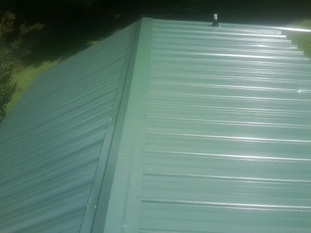 New green metal panels meeting at the ridge of a roof — Flat Roof Repair work by our crew in East Spencer
