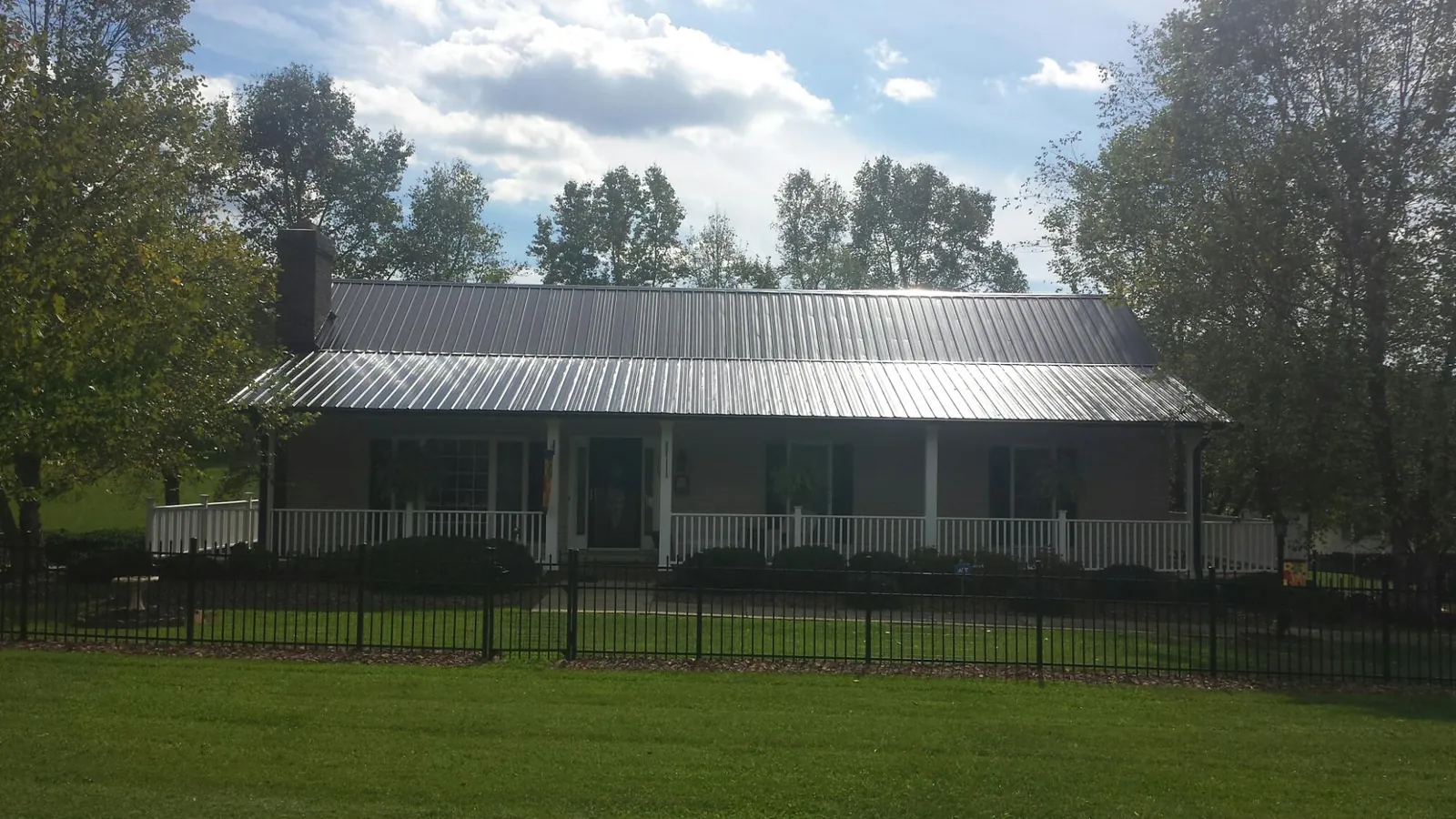 Gray metal roof on a brick ranch with a full width front porch — Gutter Guard Installation work by our crew in East Spencer